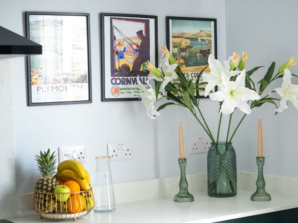 A kitchen counter with fruit bowl and floral arrangement at The Sundial in St Austell