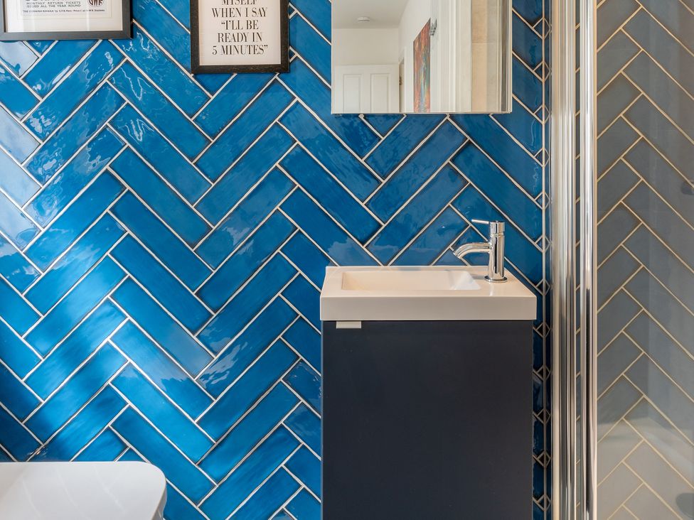 A bathroom with a sink, mirror, and shower at The Sundial in St Austell