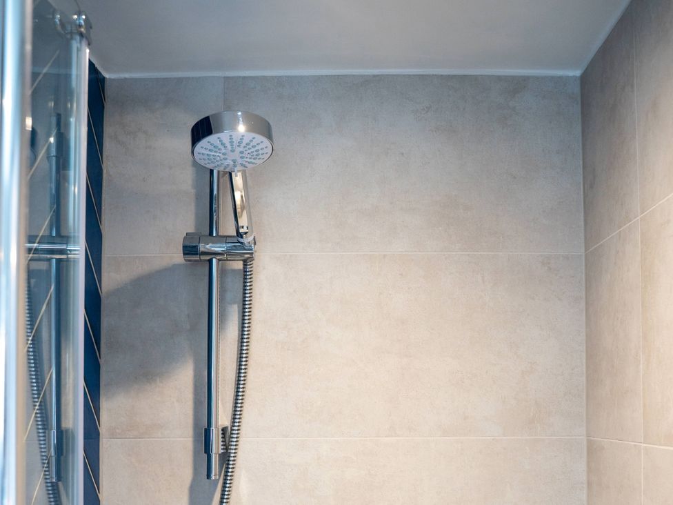 A shower with a chrome shower head in a bathroom at The Sundial in St Austell