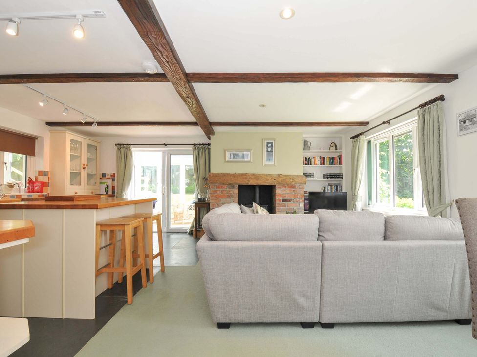 A living room with a fireplace and kitchen island at Upper Court Cottage Broad Langdon near Wainhouse Corner