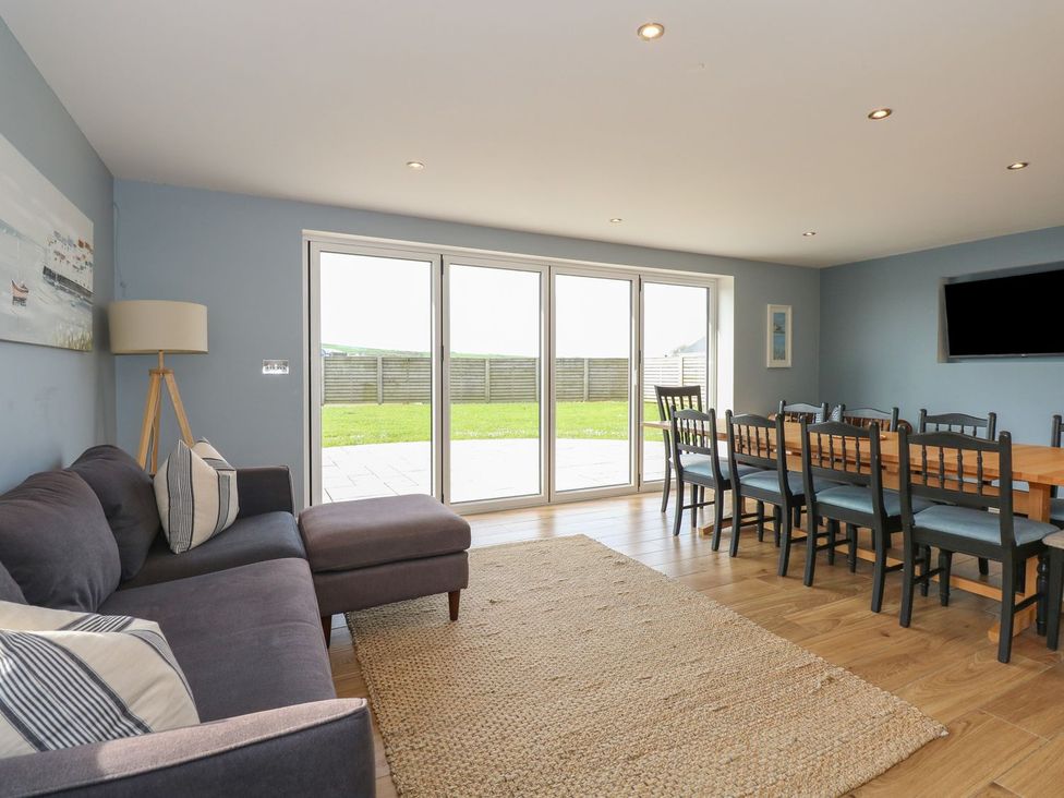 A living room with a sofa and dining table at Criw in Bryncroes near Sarn Meyllteyrn