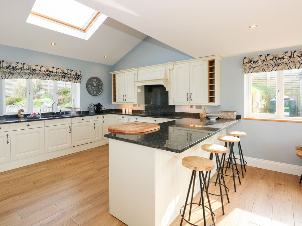 A kitchen with an island and bar stools at Criw, Bryncroes near Sarn Meyllteyrn