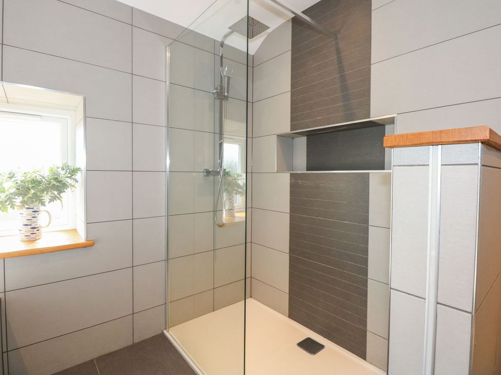 A shower with glass wall and window at Criw in Bryncroes near Sarn Meyllteyrn
