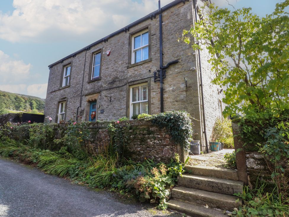 A stone house with a garden and pathway at Langcliffe House Kettlewell