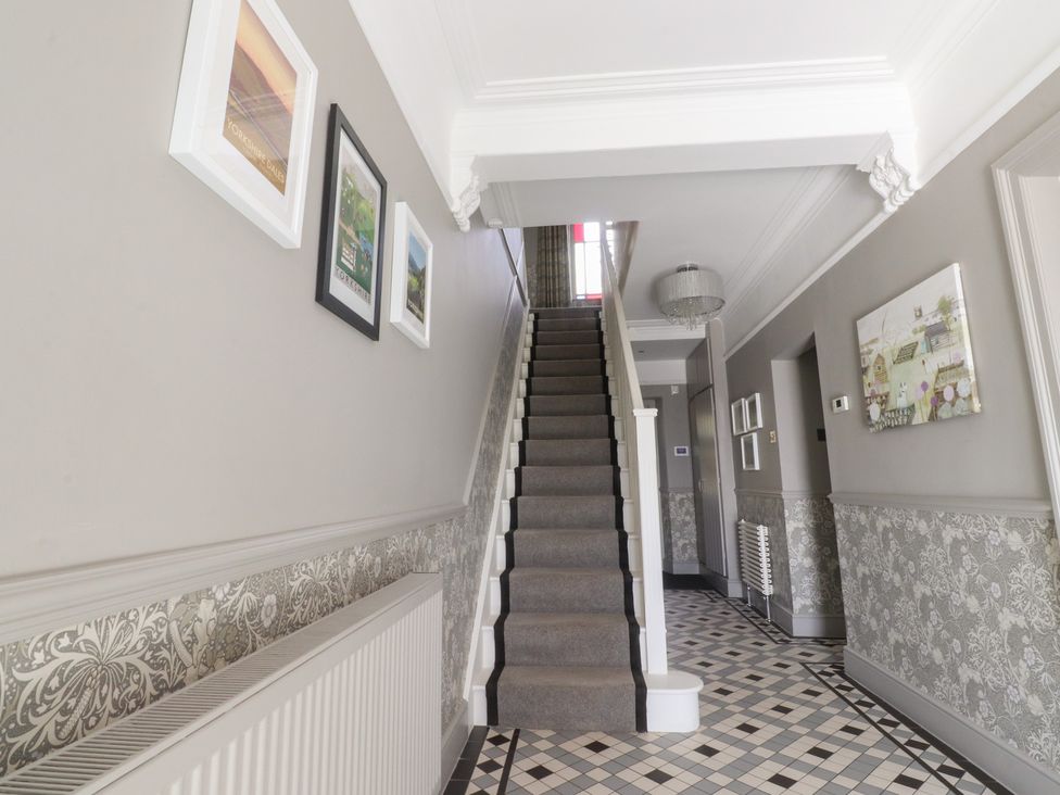A hallway with a staircase and framed pictures at Langcliffe House in Kettlewell