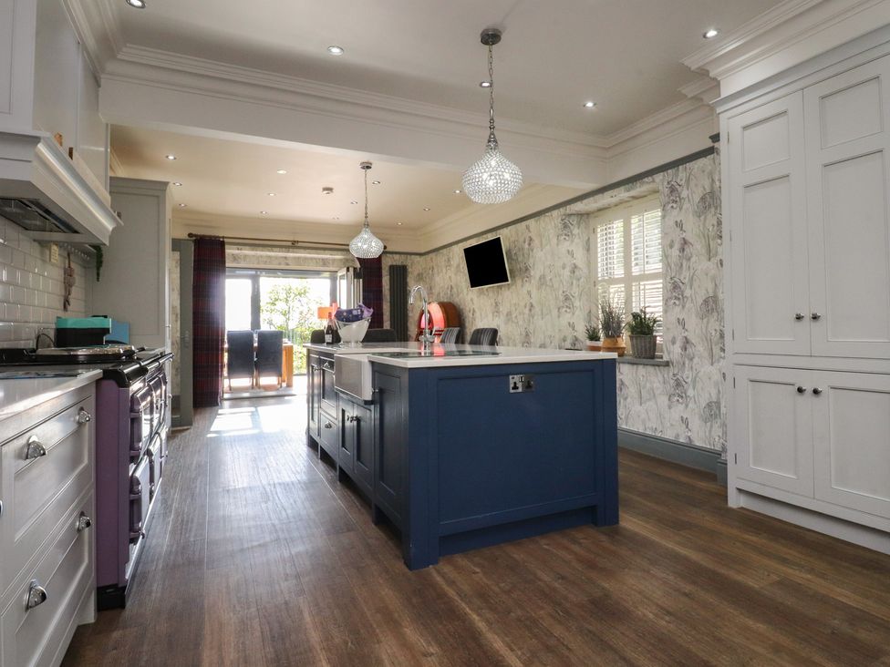 A kitchen with an island, stove, and cabinets at Langcliffe House Kettlewell