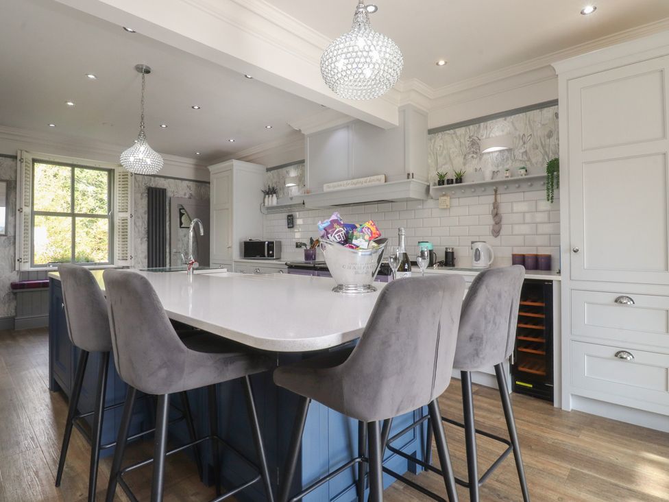 A kitchen with bar stools and an island at Langcliffe House in Kettlewell