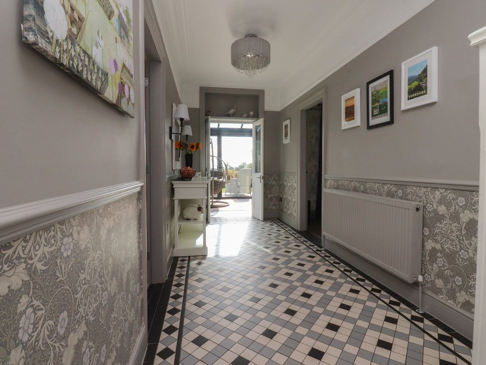 A hallway with floor tiles and wall art at Langcliffe House in Kettlewell