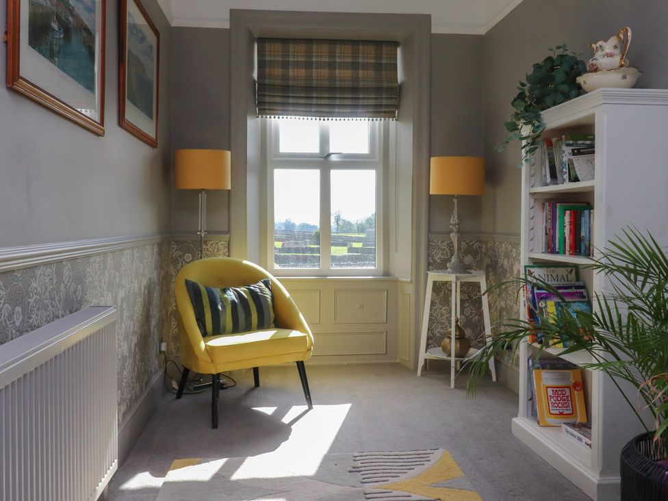 A snug with a yellow chair and a bookcase at Langcliffe House in Kettlewell