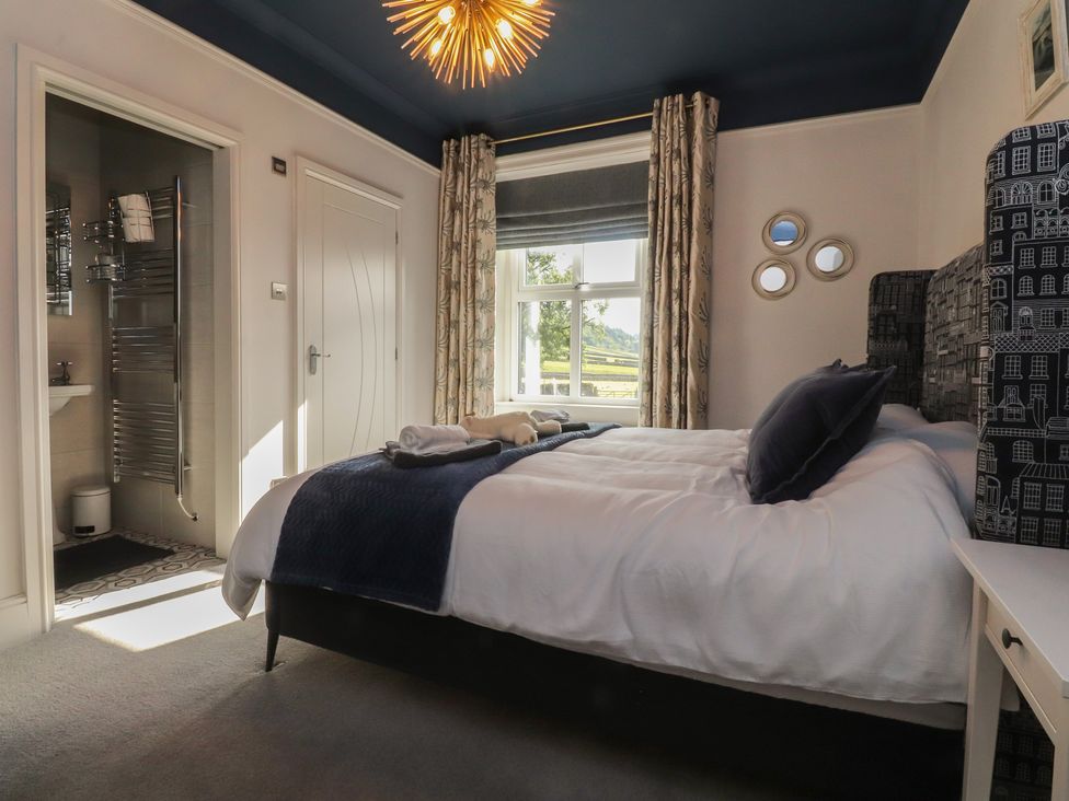 A bedroom with a bed and windows at Langcliffe House in Kettlewell