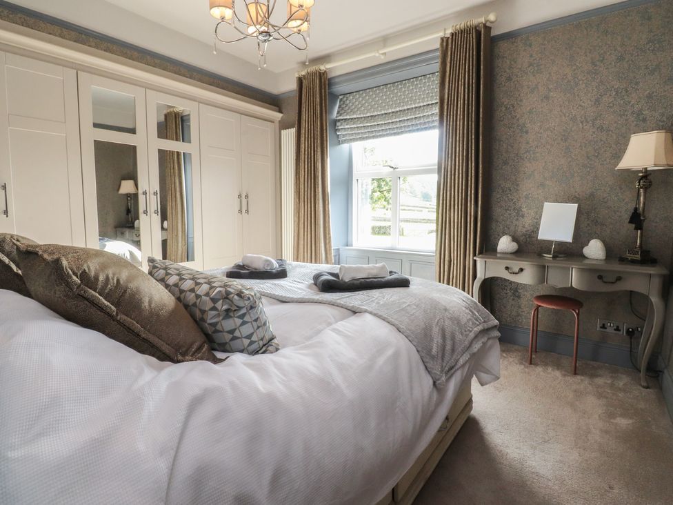 A bedroom with a bed and a wardrobe at Langcliffe House Kettlewell