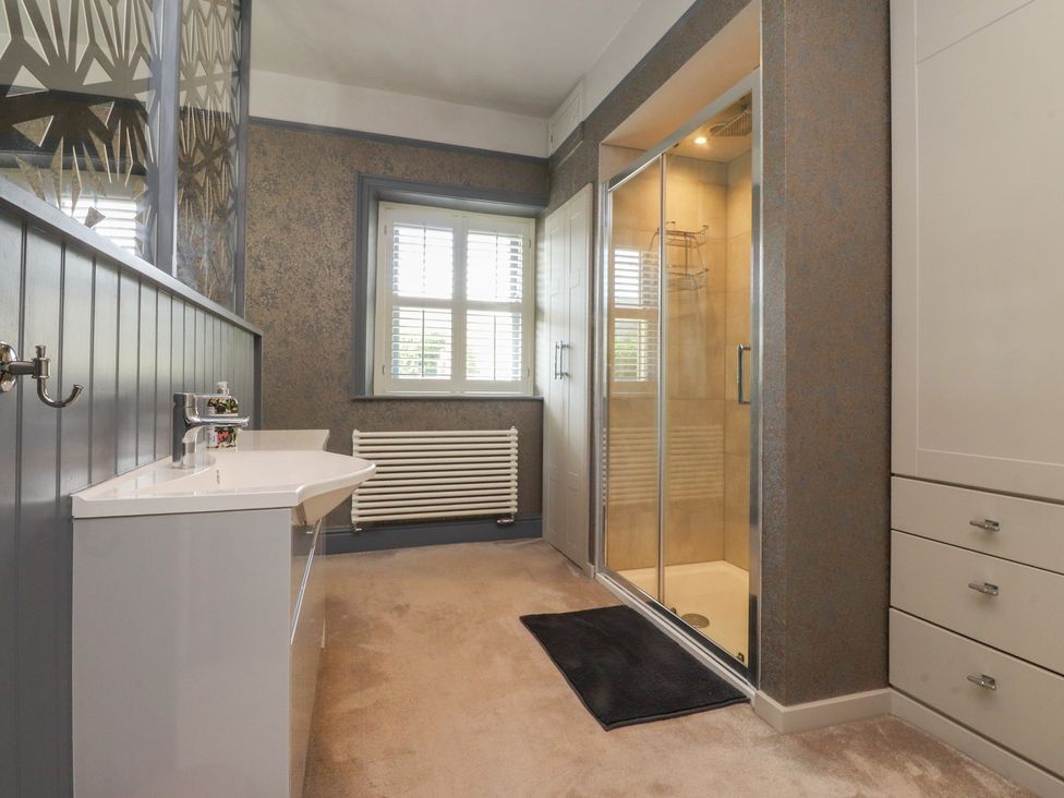 A bathroom with a sink, shower, and window at Langcliffe House in Kettlewell