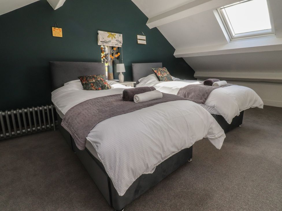 A bedroom with two beds and a bedside lamp at Langcliffe House in Kettlewell