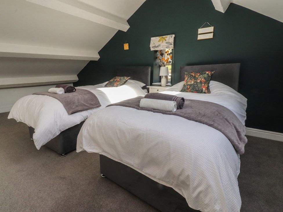 A bedroom with two beds and a lamp at Langcliffe House in Kettlewell
