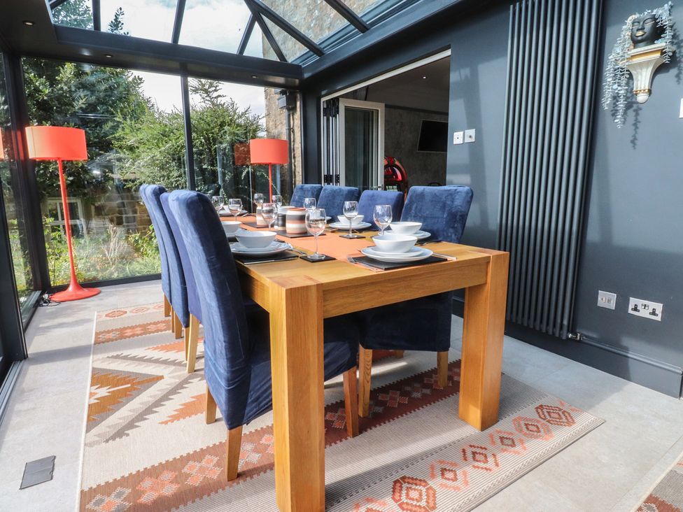 A dining table with chairs in a conservatory at Langcliffe House in Kettlewell