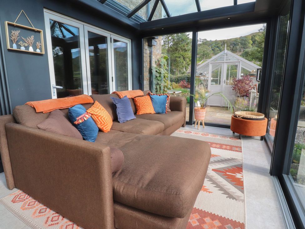 A conservatory with a sofa and glass doors at Langcliffe House in Kettlewell