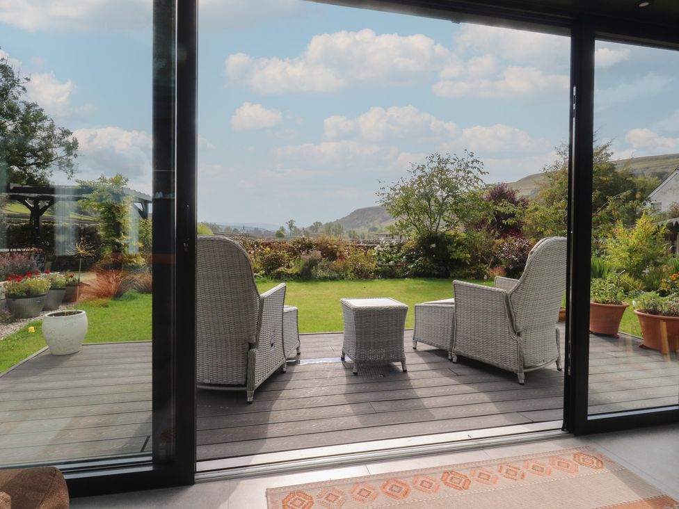 A garden with chairs and a table overlooking the landscape at Langcliffe House Kettlewell
