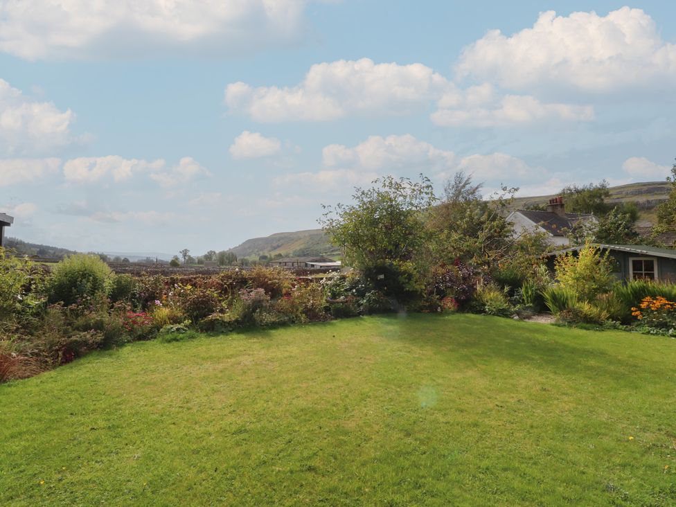 A garden with grass and flower beds at Langcliffe House in Kettlewell