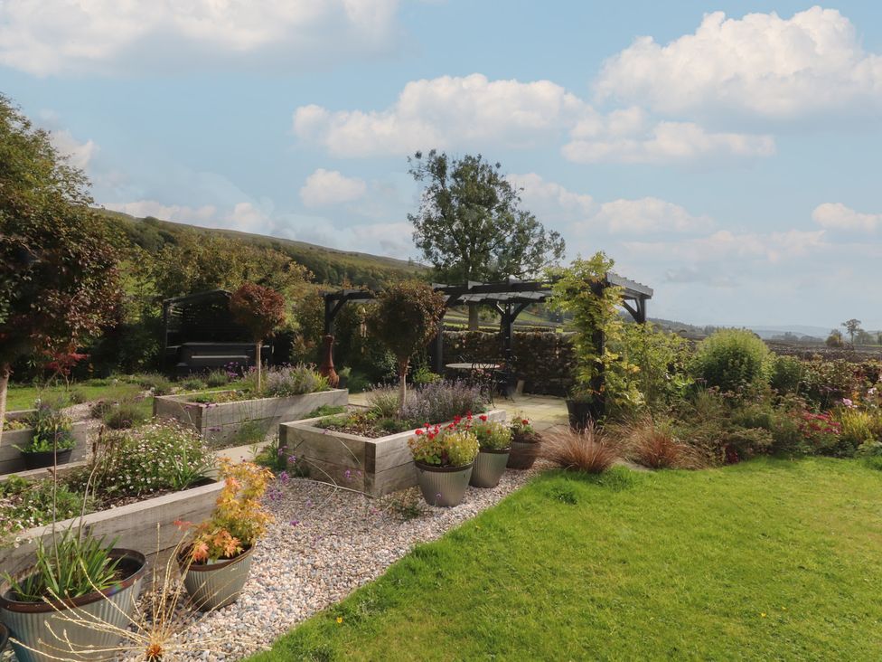 A garden with planters and a pergola at Langcliffe House in Kettlewell
