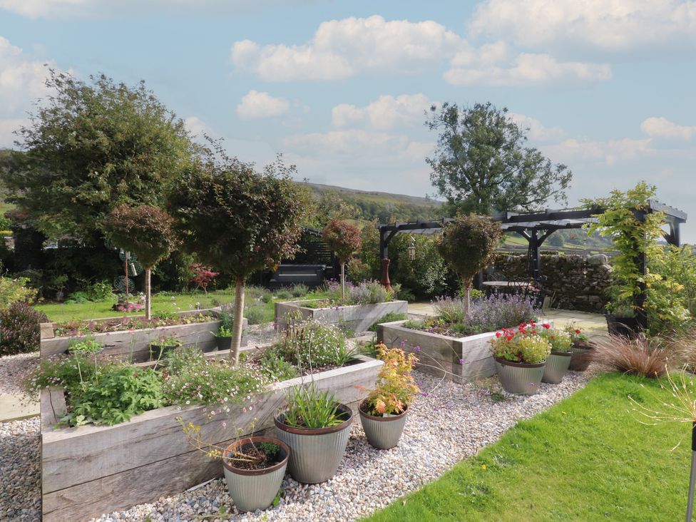 A garden with flower pots and raised beds at Langcliffe House, Kettlewell