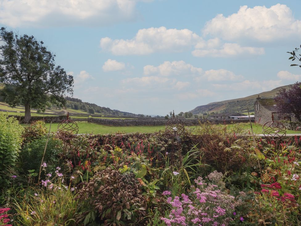 A garden with flowers and a view of mountains at Langcliffe House in Kettlewell