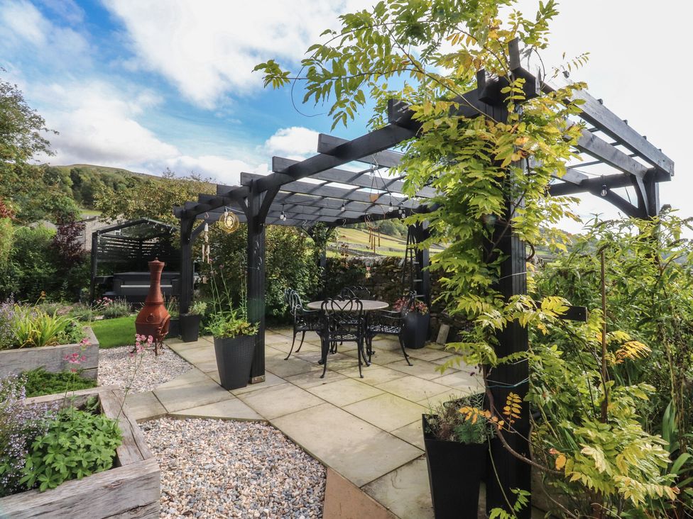 A garden with a pergola and seating area at Langcliffe House Kettlewell