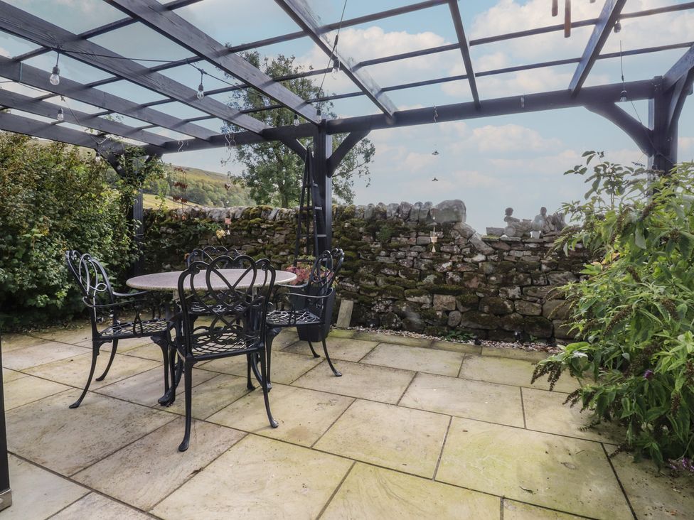 An outdoor seating area with a table and chairs at Langcliffe House in Kettlewell