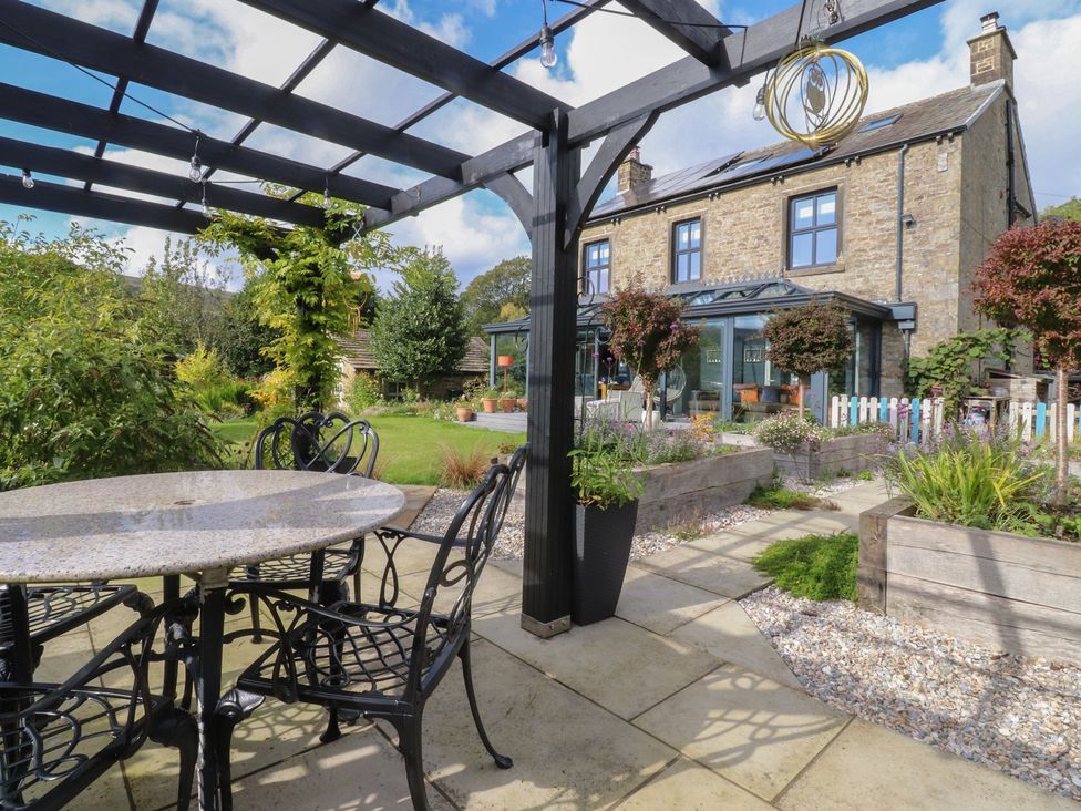A garden with a table and chairs under a pergola at Langcliffe House in Kettlewell