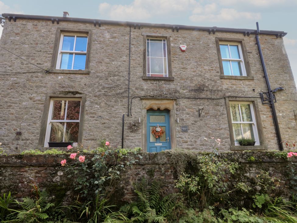 A house with a stone exterior and blue front door at Langcliffe House Kettlewell