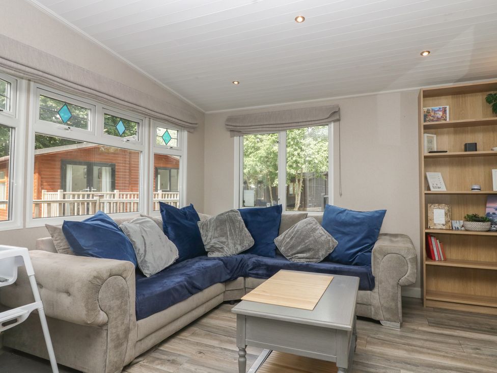A living room with a sofa and bookshelf at Owls Nook Lodge, Langdale 9, White Cross Bay near Windermere