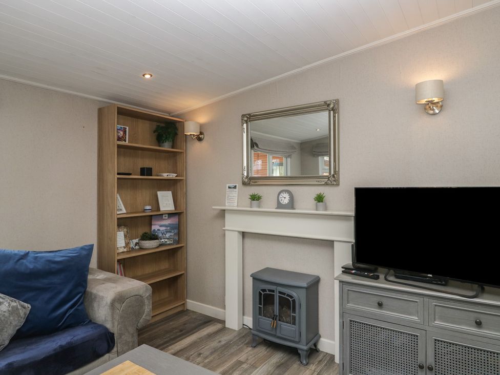 A living room with a shelf, mirror, and fireplace at Owls Nook Lodge, Langdale 9, White Cross Bay near Windermere