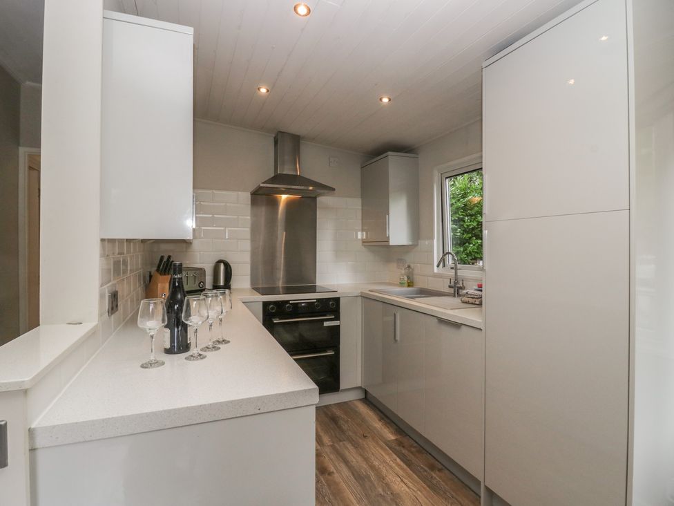 A kitchen with cabinets, sink, and oven at Owls Nook Lodge in Langdale 9, White Cross Bay near Windermere