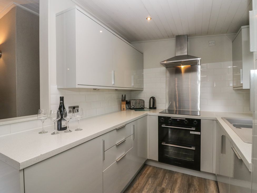 A kitchen with a cooker and wine glasses at Owls Nook Lodge Langdale 9, White Cross Bay near Windermere