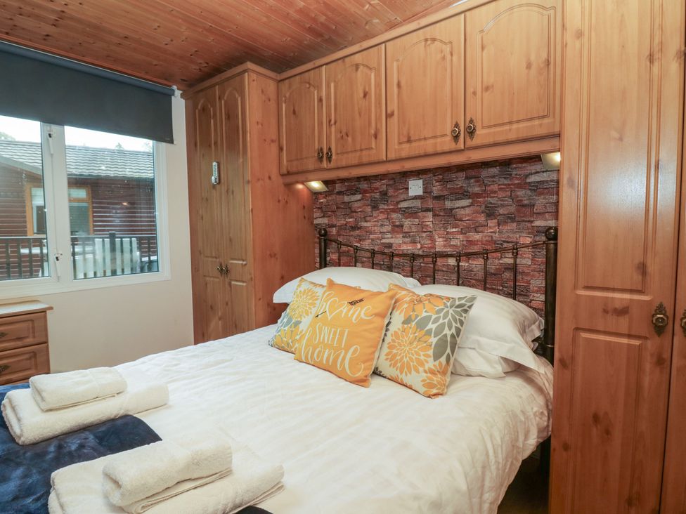 A bedroom with a bed and wardrobe at Owls Nook Lodge Langdale 9, White Cross Bay near Windermere