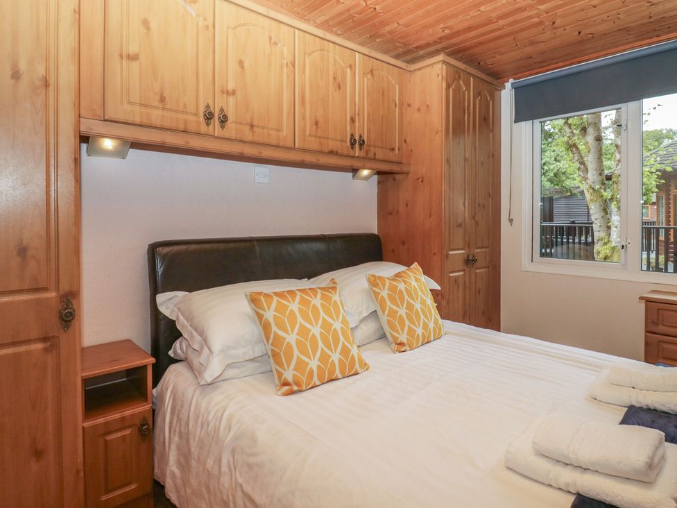 A bedroom with a bed and wooden furniture at Owls Nook Lodge, Langdale 9, White Cross Bay near Windermere