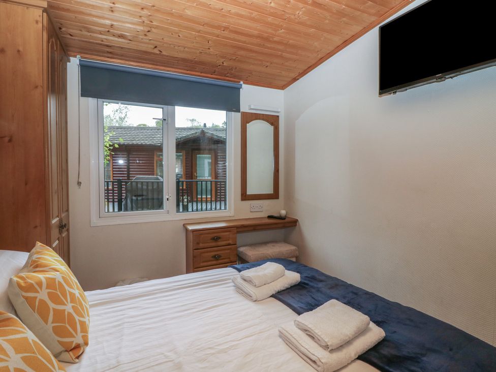 A bedroom with a bed and television at Owls Nook Lodge, Langdale 9, White Cross Bay near Windermere