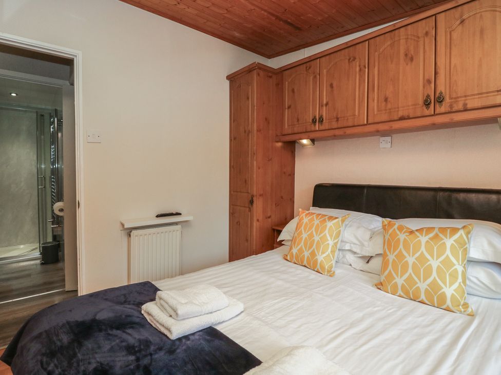 A bedroom with a bed and wardrobe at Owls Nook Lodge, Langdale 9, White Cross Bay near Windermere