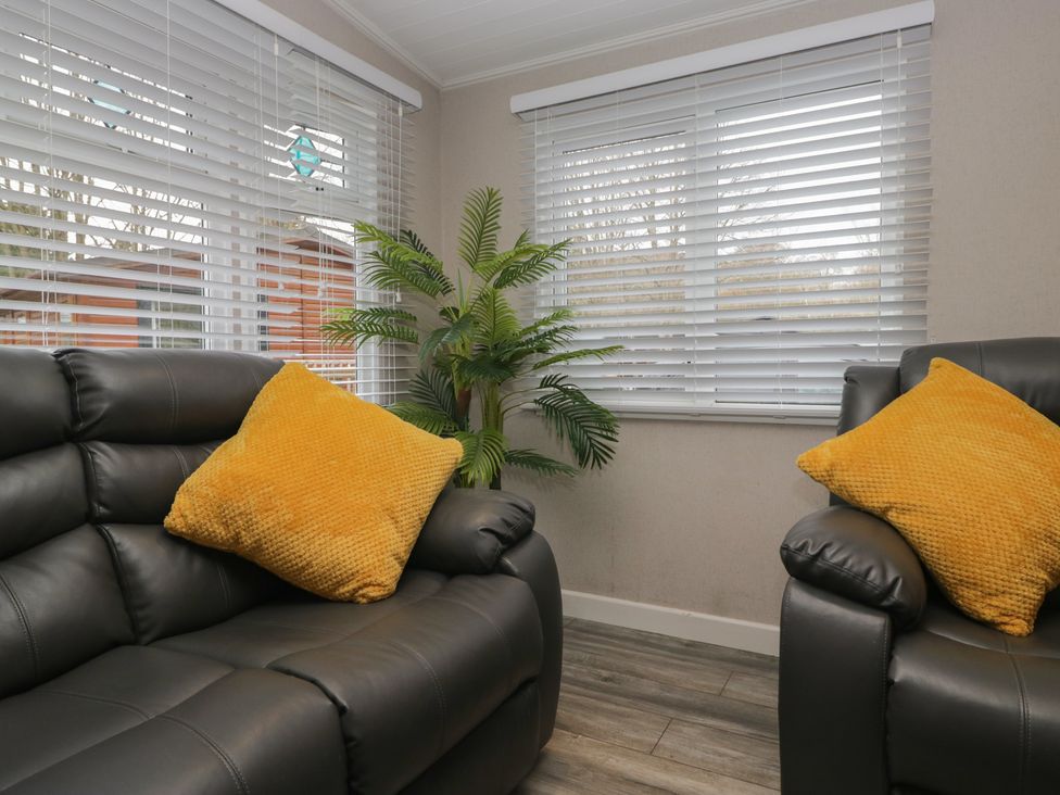 Two armchairs with cushions and a plant in a living room at Owls Nook Lodge Langdale 9 White Cross Bay near Windermere