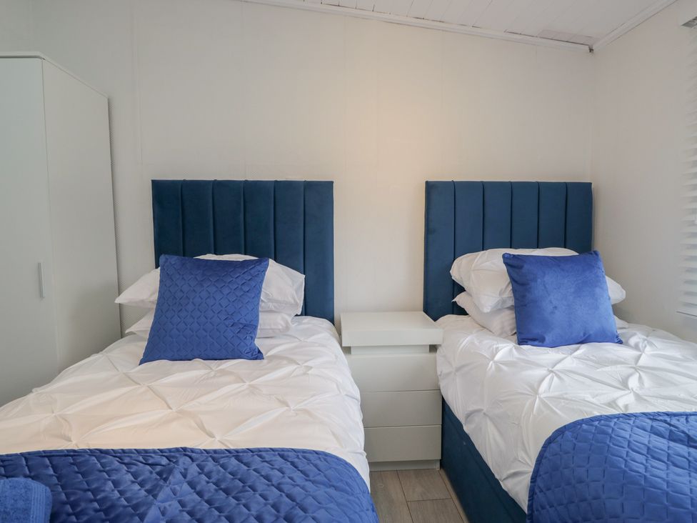 A bedroom with two twin beds and a bedside table at Owls Nook Lodge, Langdale 9, White Cross Bay near Windermere