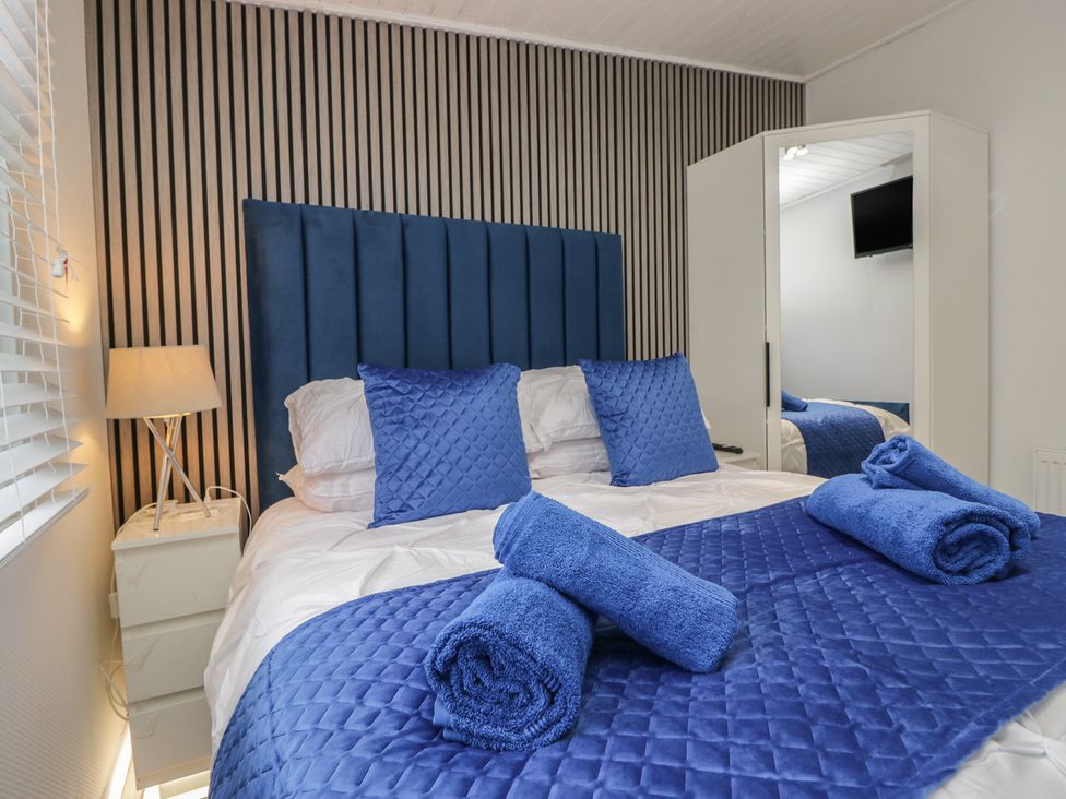 A bedroom with a bed and bedside table at Owls Nook Lodge in Langdale 9, White Cross Bay near Windermere