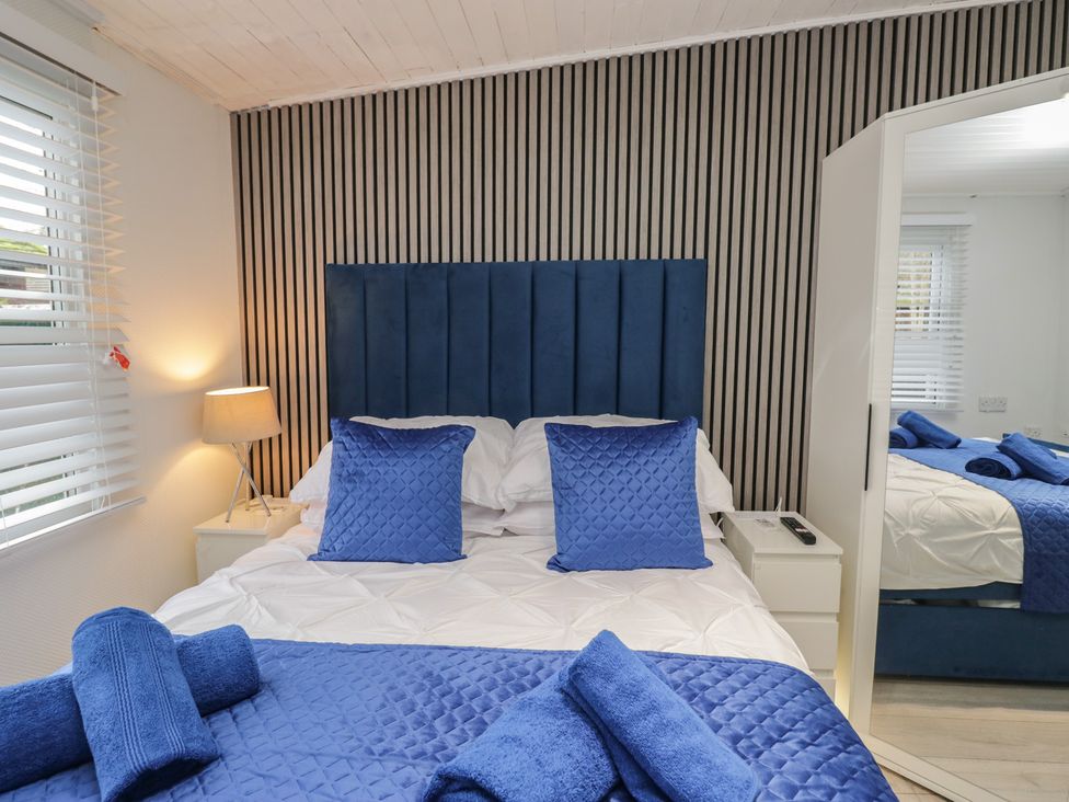 A bedroom with a bed and bedside table at Owls Nook Lodge, Langdale 9, White Cross Bay near Windermere