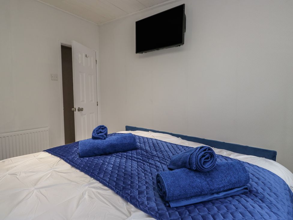 A bedroom with a bed and towels at Owls Nook Lodge, Langdale 9, White Cross Bay near Windermere