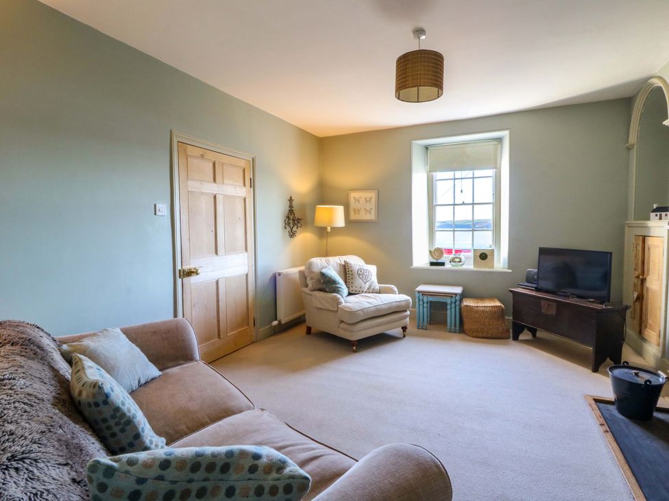 A living room with a sofa and a television at Zenobia in New Quay