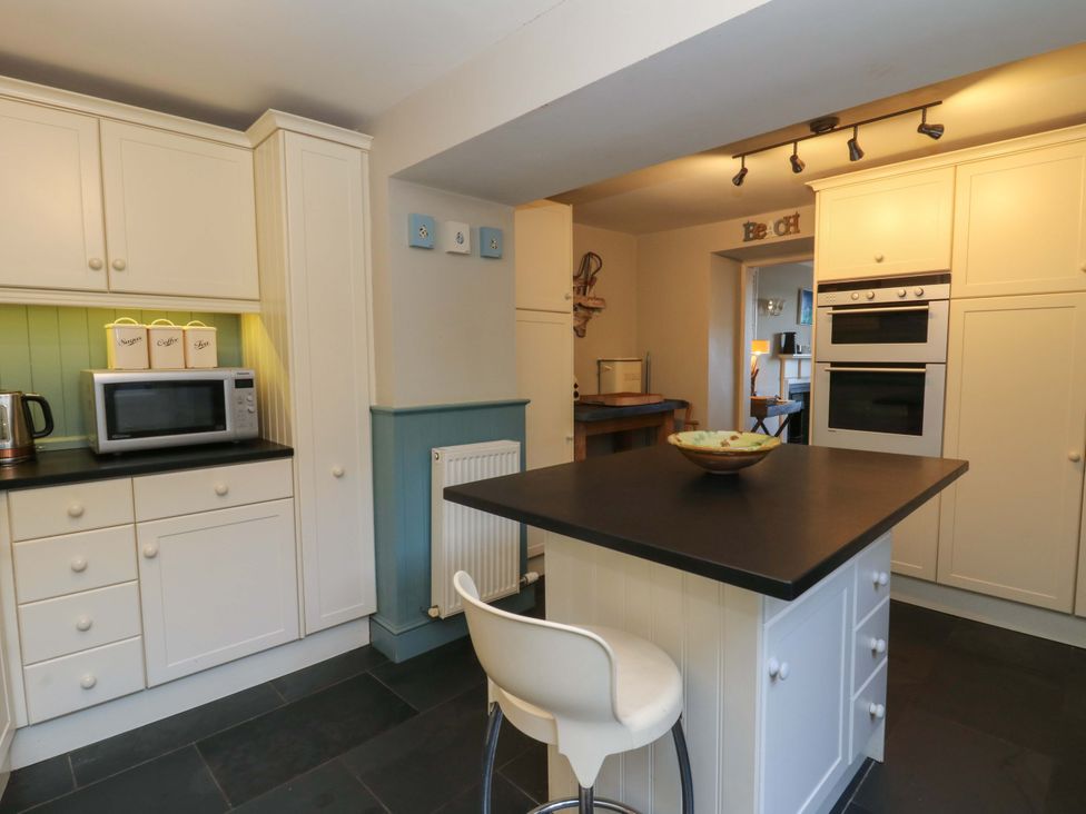 A kitchen with cabinets and a microwave at Zenobia in New Quay