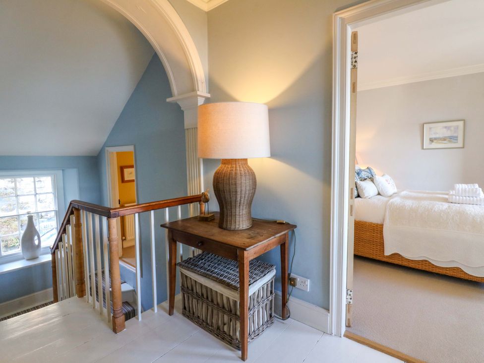 A hallway with a lamp and table at Zenobia in New Quay