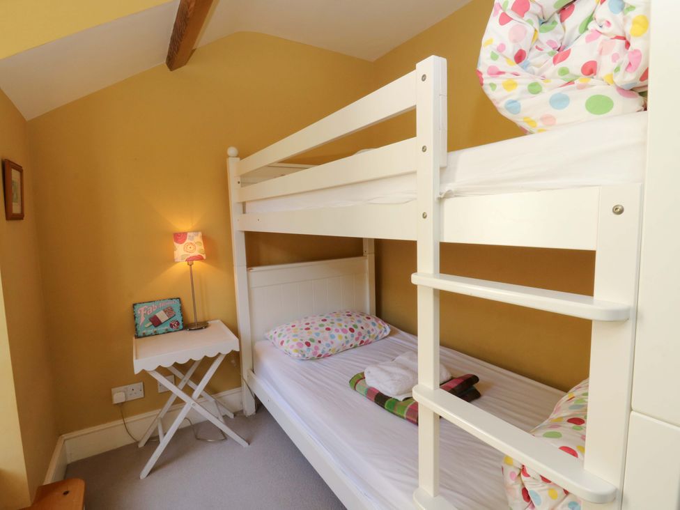 A bedroom with a bunk bed and side table at Zenobia in New Quay