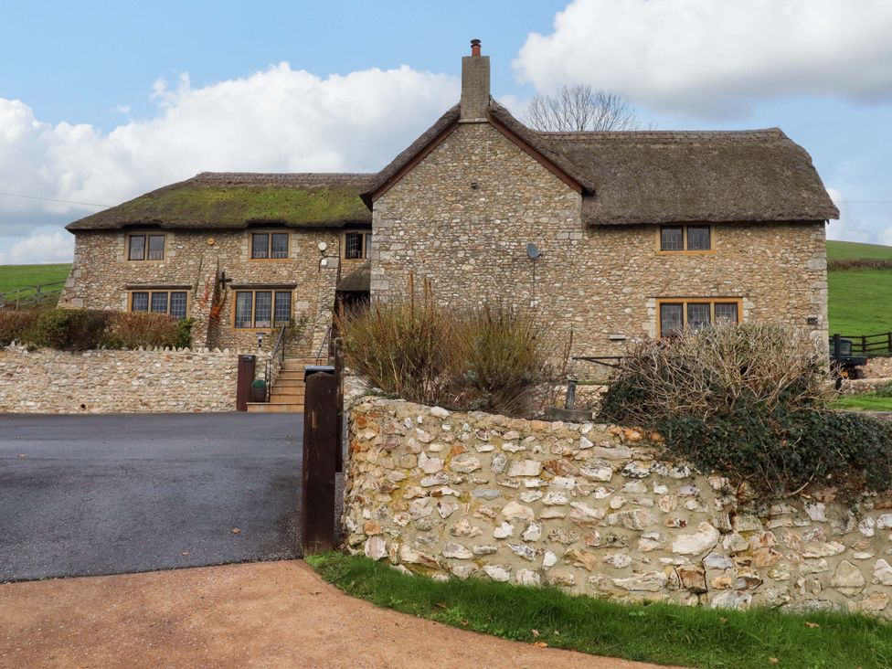 A house with a thatched roof and stone walls at Higher Wadden Farm Southleigh