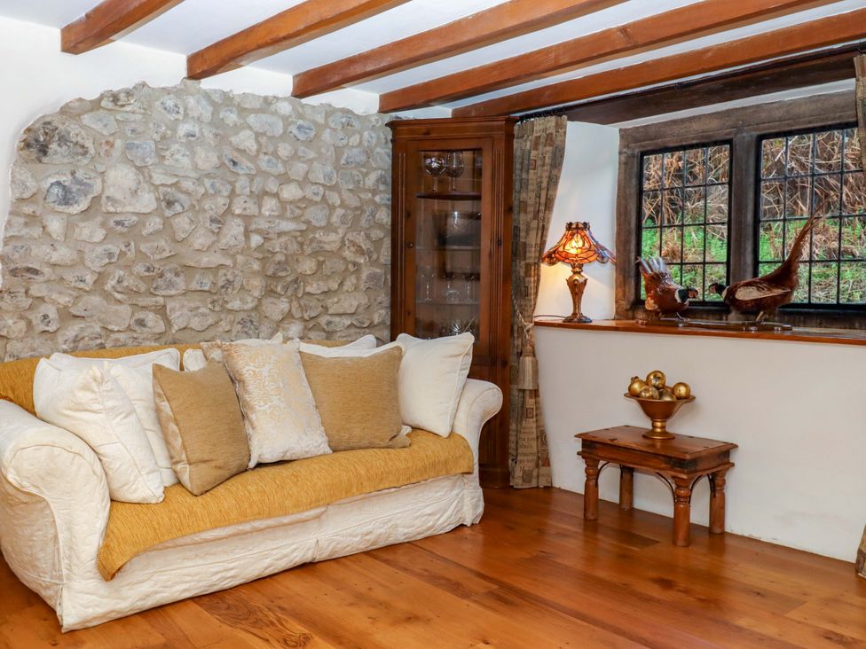 A living room with a sofa and display cabinet at Higher Wadden Farm Southleigh