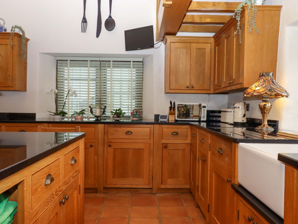 A kitchen with wooden cabinets and a sink at Higher Wadden Farm in Southleigh