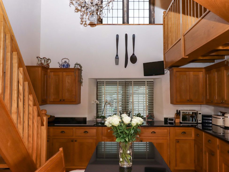 A kitchen with wooden cabinets and a vase of flowers at Higher Wadden Farm Southleigh